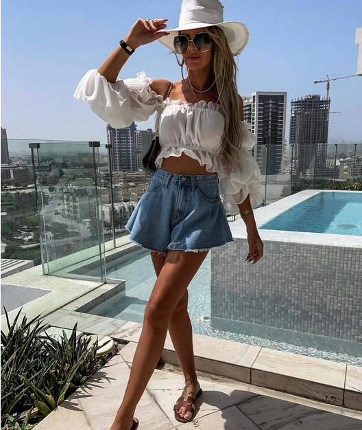 High-waisted flared denim shorts on balcony in sunlight